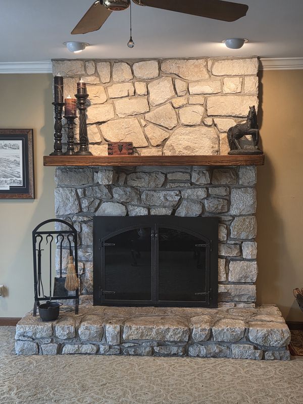 Floor-to-ceiling real stone fireplace with a wood mantel